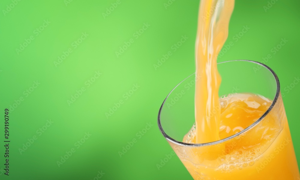 Orange juice pouring in glass on background