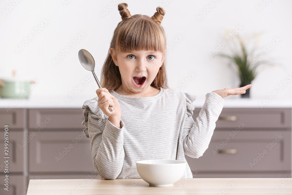 Surprised little girl eating in kitchen