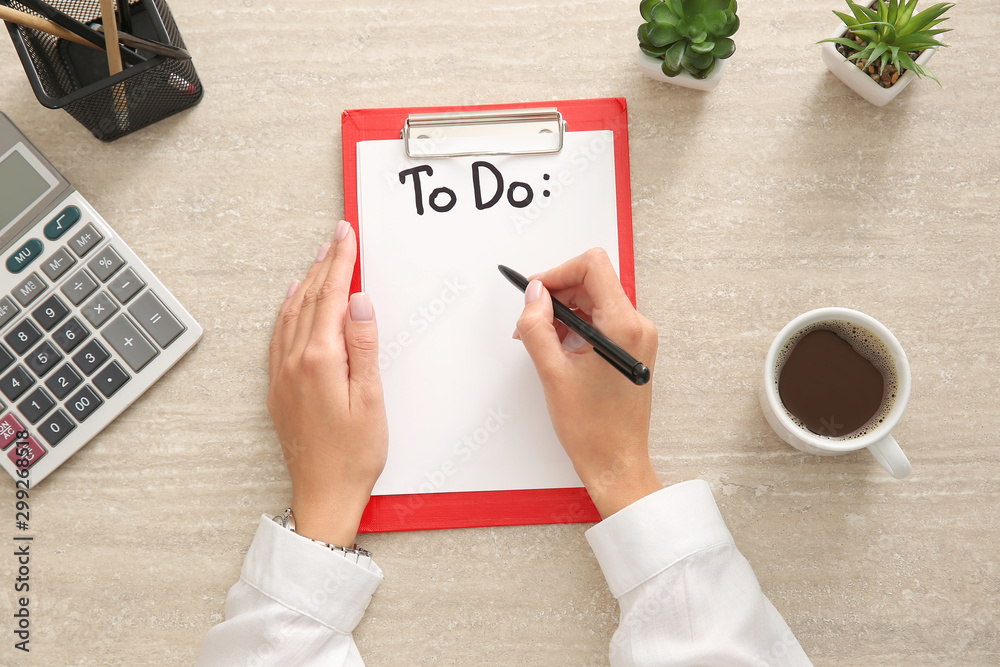 Woman making to-do list at table, top view