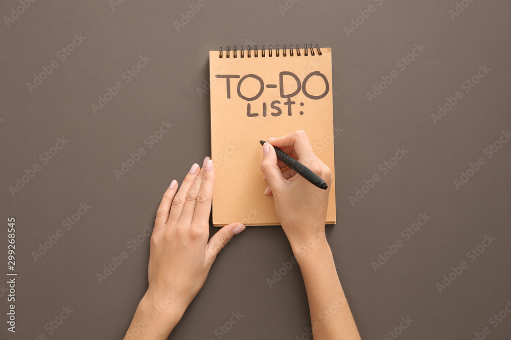 Woman making to-do list on grey background