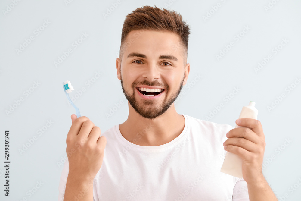 Man with toothbrush and paste on light background