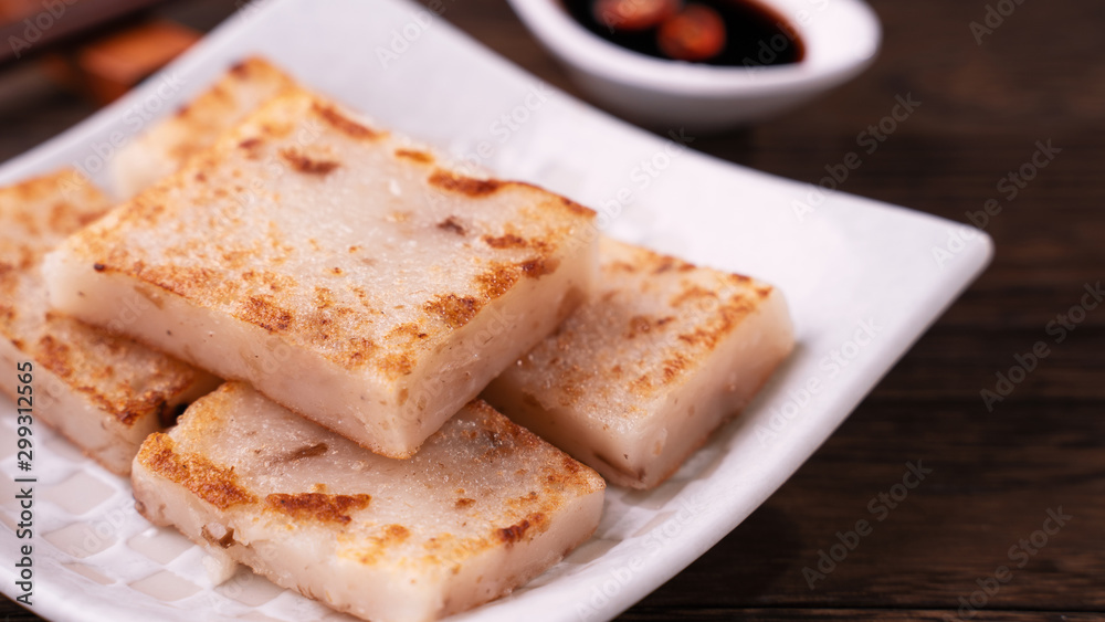 Delicious turnip cake, Chinese traditional local dish radish cake in restaurant with soy sauce and c