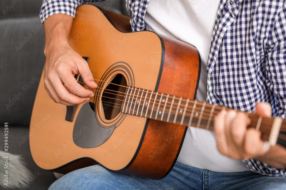 Man playing guitar at home, closeup