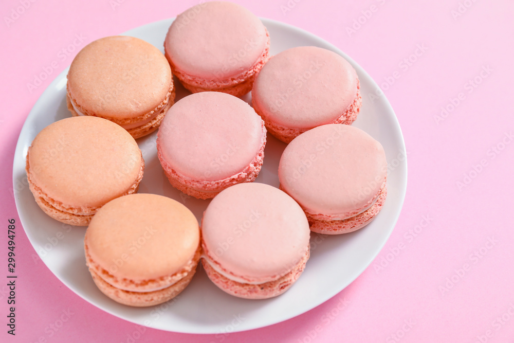 Plate with tasty macarons on color background