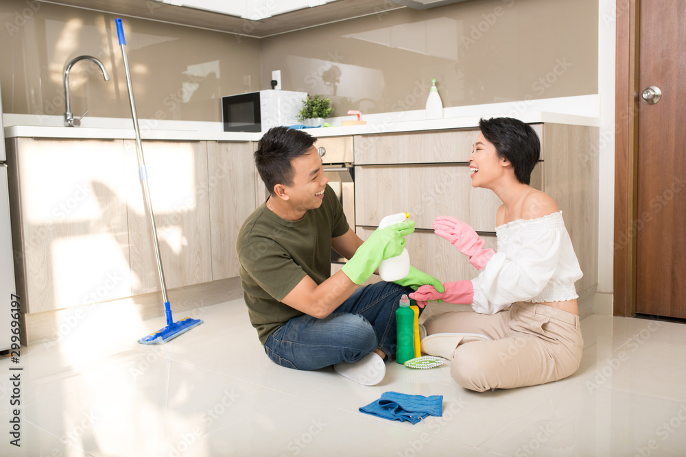 Young happy Asian couple is having fun while doing cleaning at home.