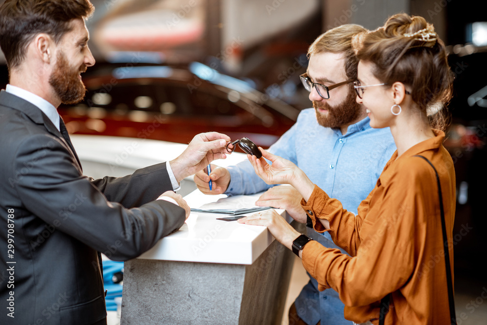 Sales manager with a young couple buying a new car