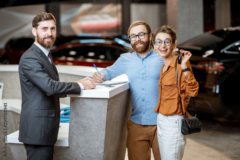 Sales manager with a young couple buying a new car