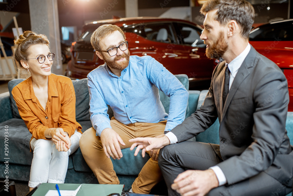 Young couple with saller on the couch at the car dealership