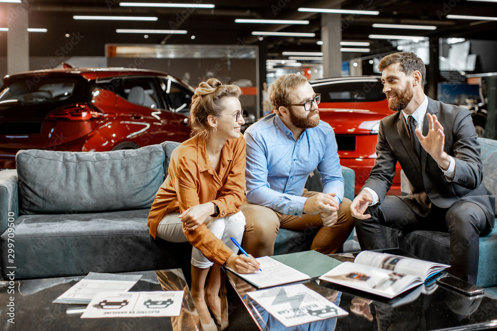 Young couple with saller on the couch at the car dealership