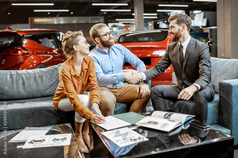 Young couple with saller on the couch at the car dealership