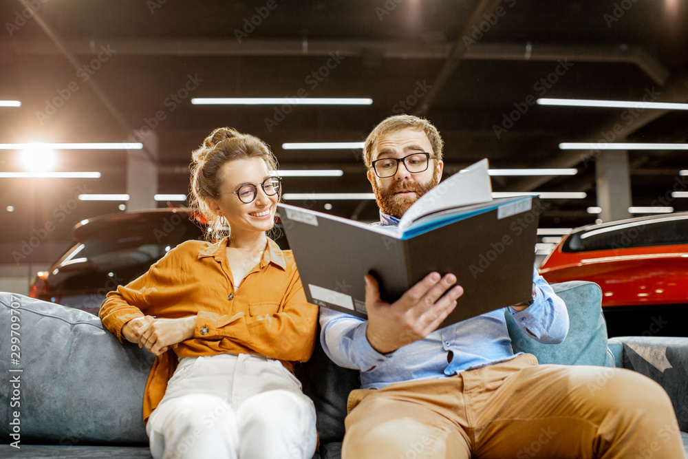 Couple with catalog on the couch at the car dealership