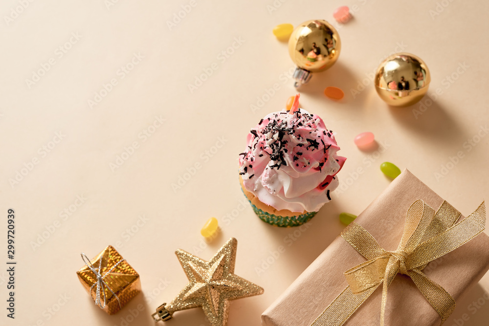 Christmas card. Cupcake with gift boxes, ornament and candies on light yellow background. Holidays.