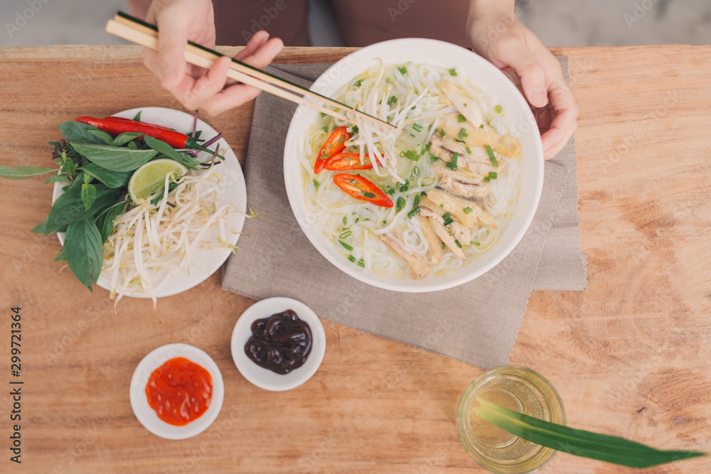 Pho Bo - Vietnamese fresh rice noodle soup with beef, herbs and chili. Stock being poured. Vietnams