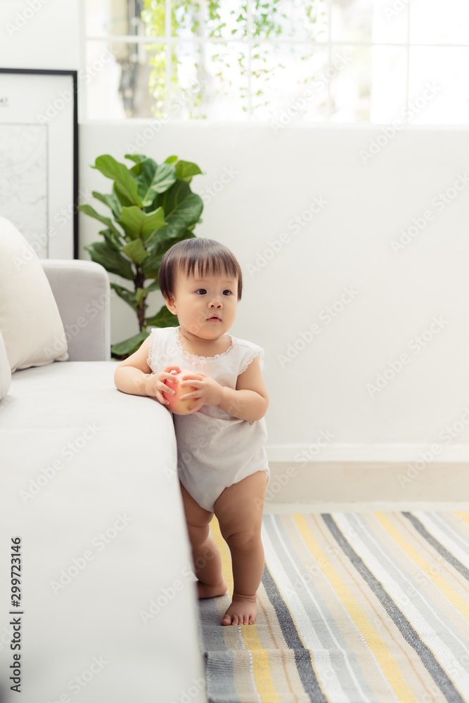 Little girl stands near the sofa at home