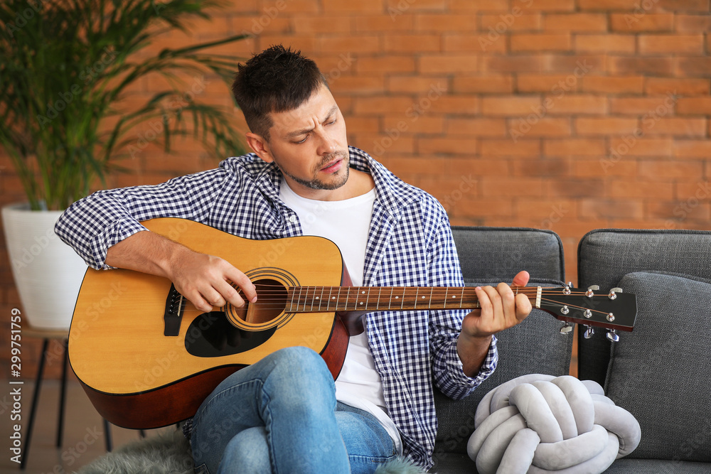 Handsome man playing guitar at home