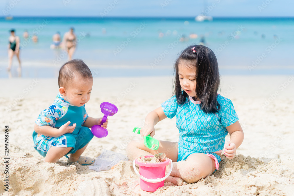 4 years old Little asian girl playing on the beach with her 1 year old baby brother.Children in natu