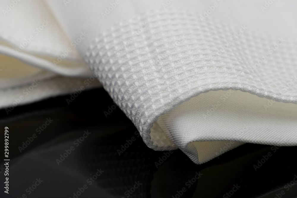 Macro shot texture of folded white towel kitchen fabric isolated on black background