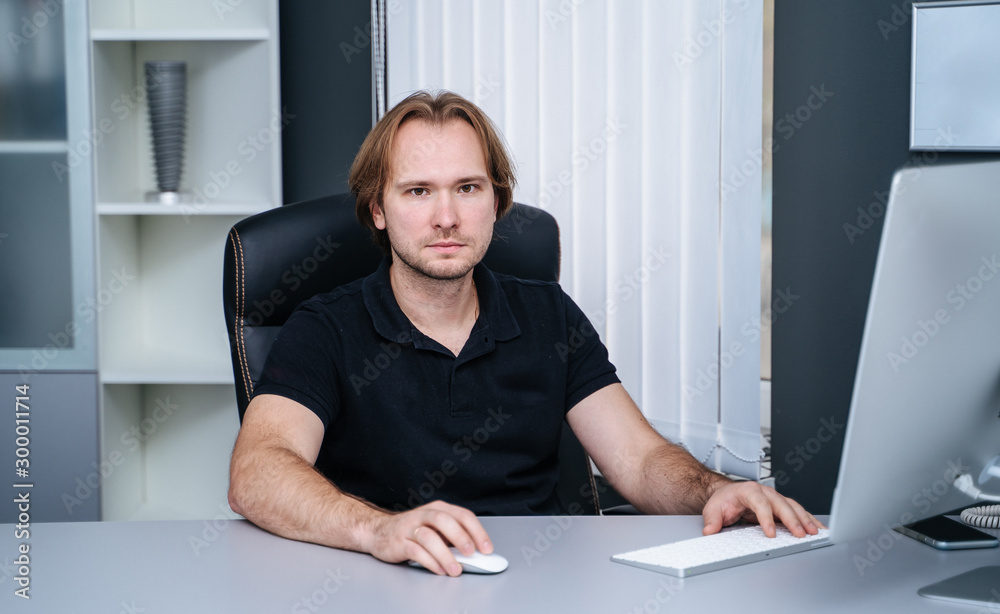 Portrait of a young specialist at his office. Confident male doctor is sitting at desk in medical ca