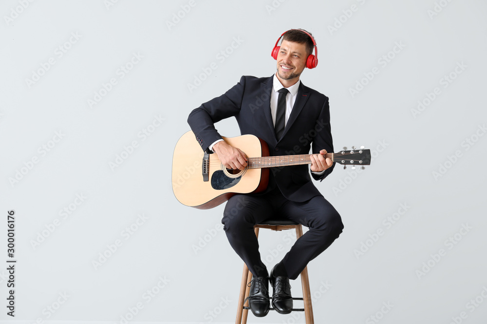 Handsome man playing guitar on light background