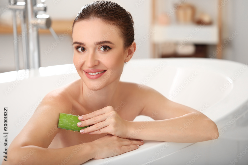 Beautiful young woman using aloe vera in bathroom