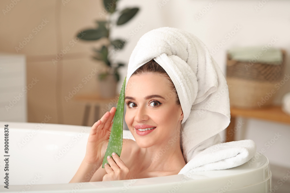 Beautiful young woman with aloe vera in bathroom