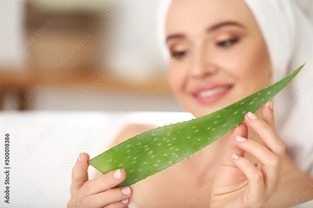 Beautiful young woman with aloe vera in bathroom