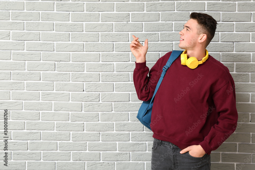 Portrait of teenage boy pointing at something on brick background