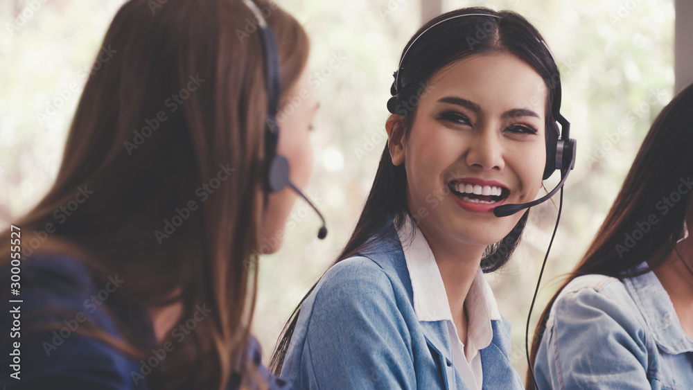 Customer support agent or call center with headset works on desktop computer while supporting the cu