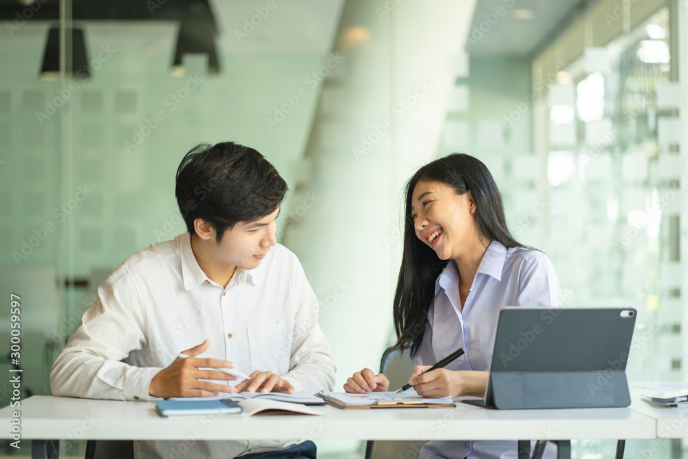 年轻的亚洲夫妇或大学生使用数字平板电脑和笔记本电脑一起工作