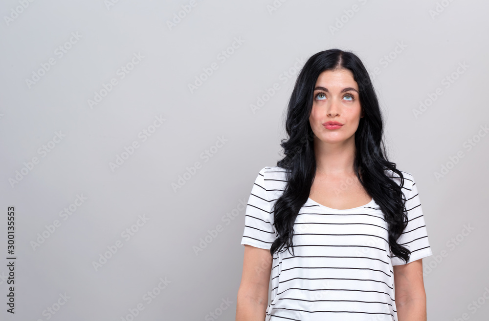 Young woman looking upwards on a gray background