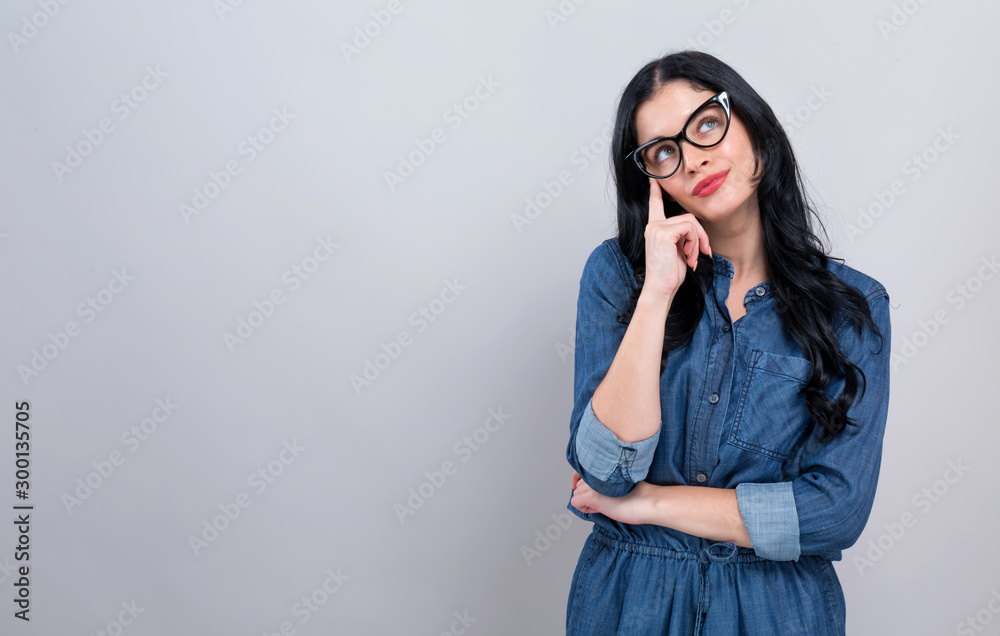 Young woman in a thoughtful pose on a gray background