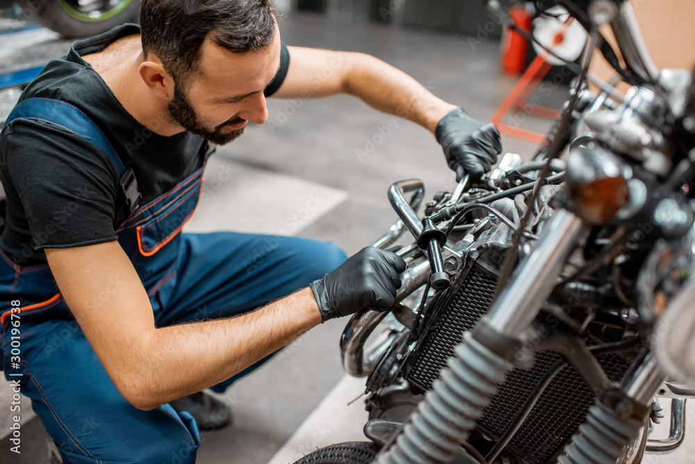 Worker repairing motorcycle engine at the workshop