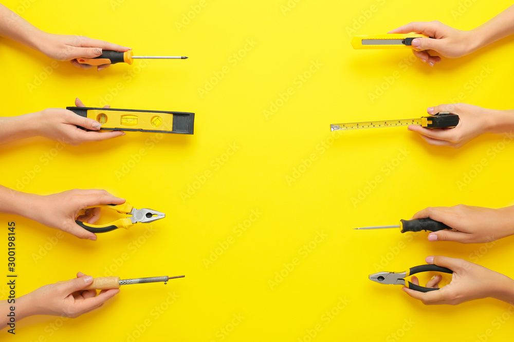 Female hands with set of electricians supplies on color background