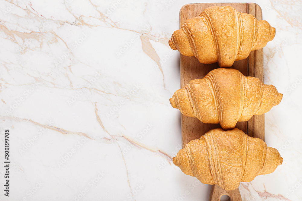 Sweet tasty croissants on light background