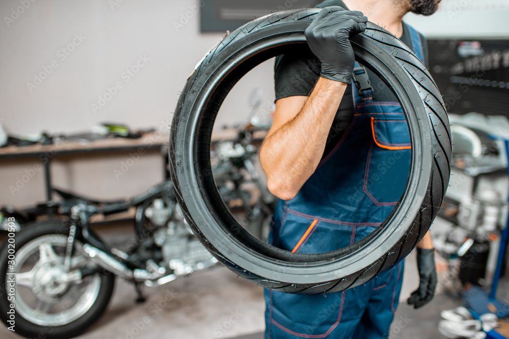 Service worker with motorcycle tire in the workshop