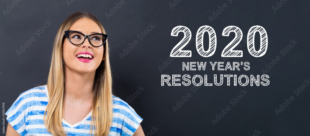 2020 New Years Resolutions with happy young woman in front of a blackboard