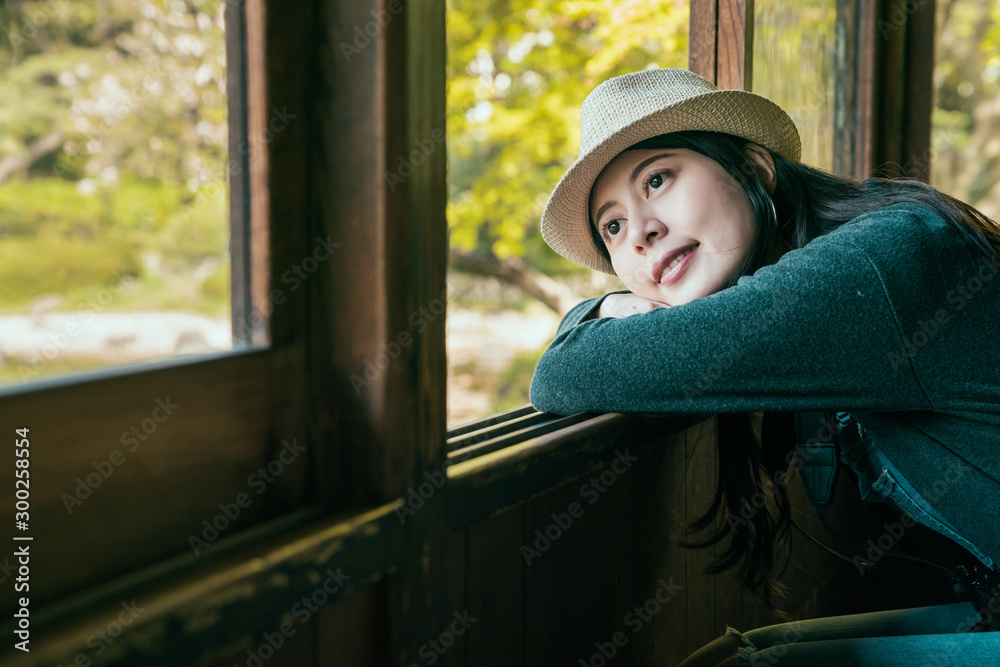 室内视图，年轻的女孩旅行者戴着草帽，靠在房子打开的窗户上。女人t