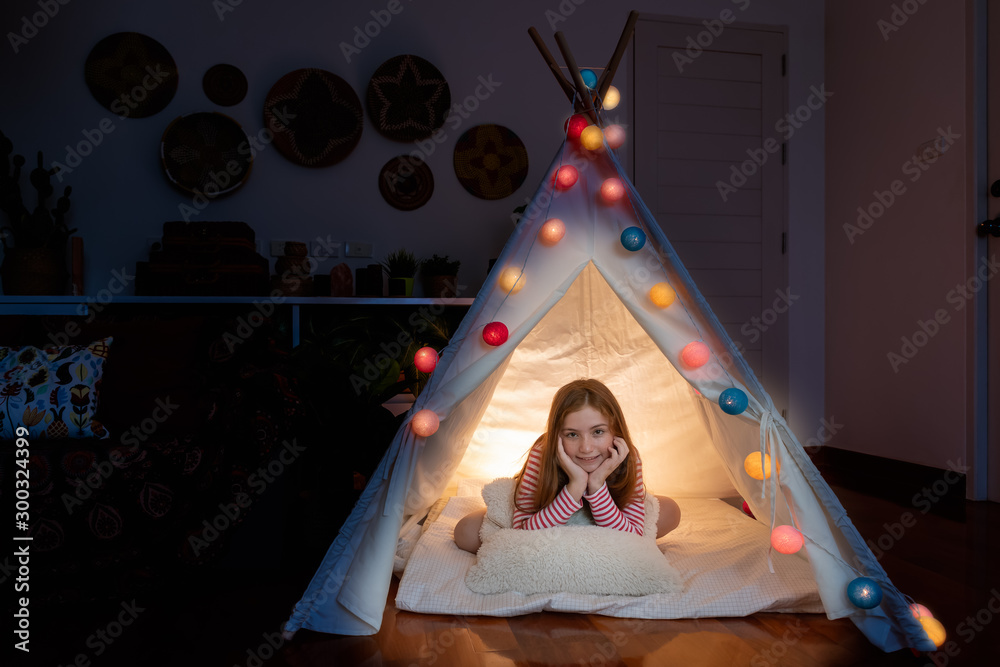 Attractive cute girl sitting inside tepee tent in her bedroom enjoy happy time.