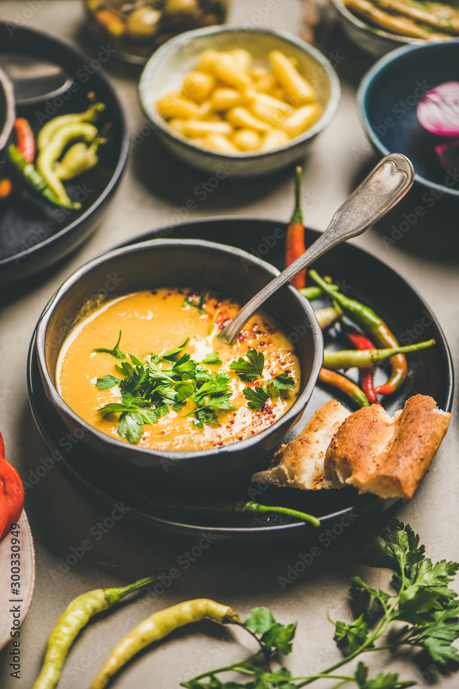 Turkish traditional lentil soup Mercimek in black bowl with parsley, vegetables, flatbread, pickled 