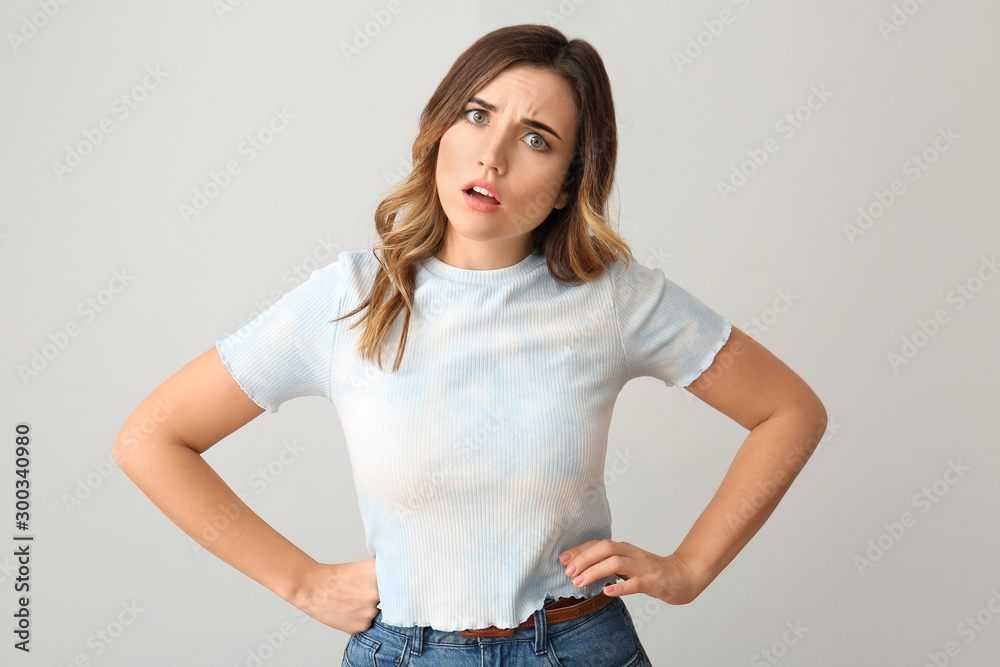 Stressed young woman on light background