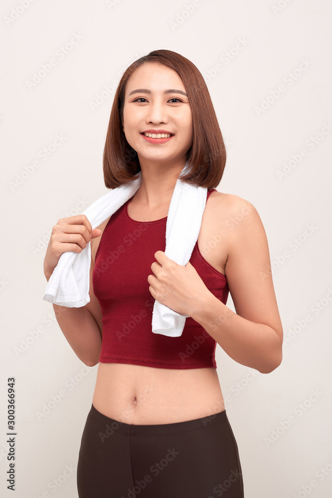 Sporty young woman with towel on light background