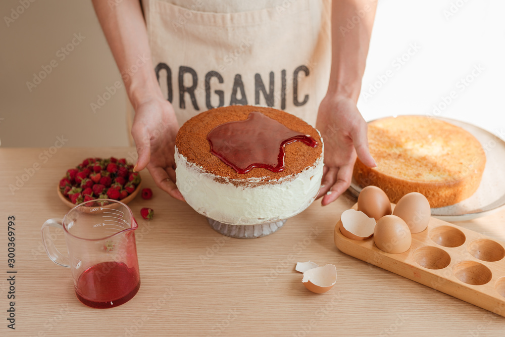 Male pastry chef holding sponge cake or red velvet cake covered syrup or jam