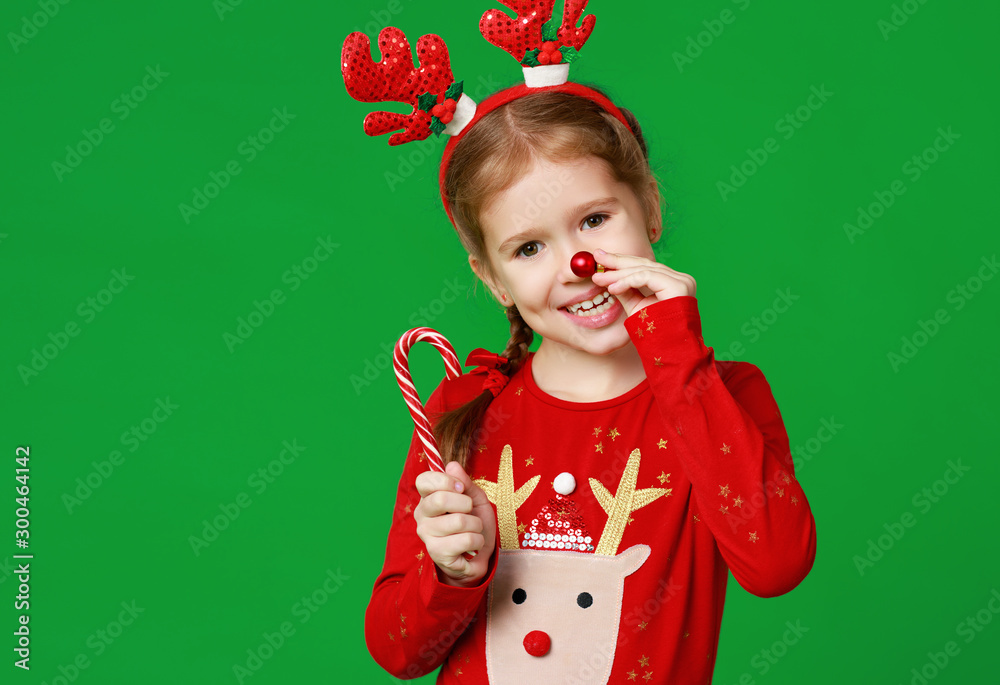 happy funny child girl in red Christmas reindeer costume with gift on green   background.