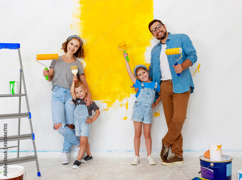 Repair in apartment. Happy family mother, father and children   paints wall .