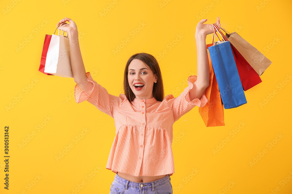 Beautiful young woman with shopping bags on color background