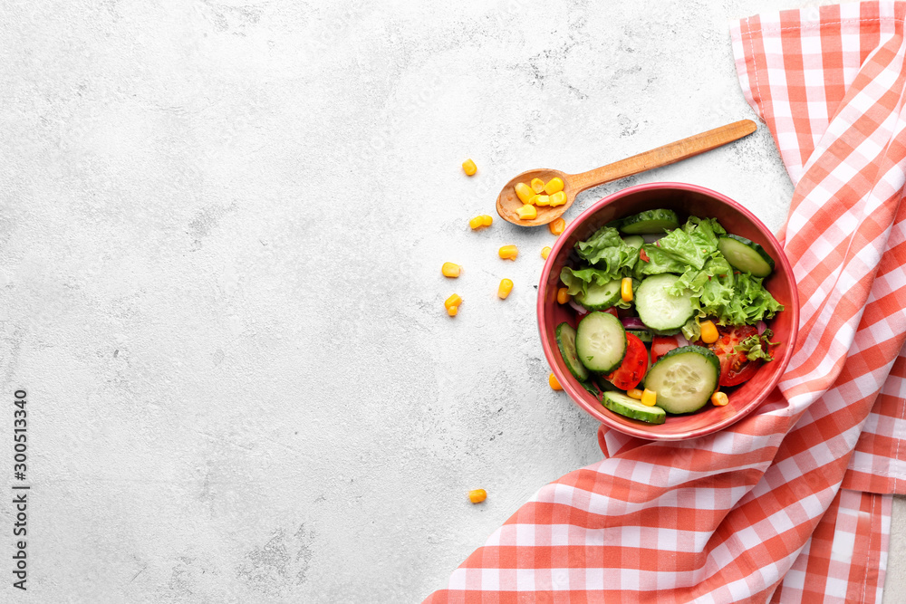 Bowl with fresh vegetable salad on light background