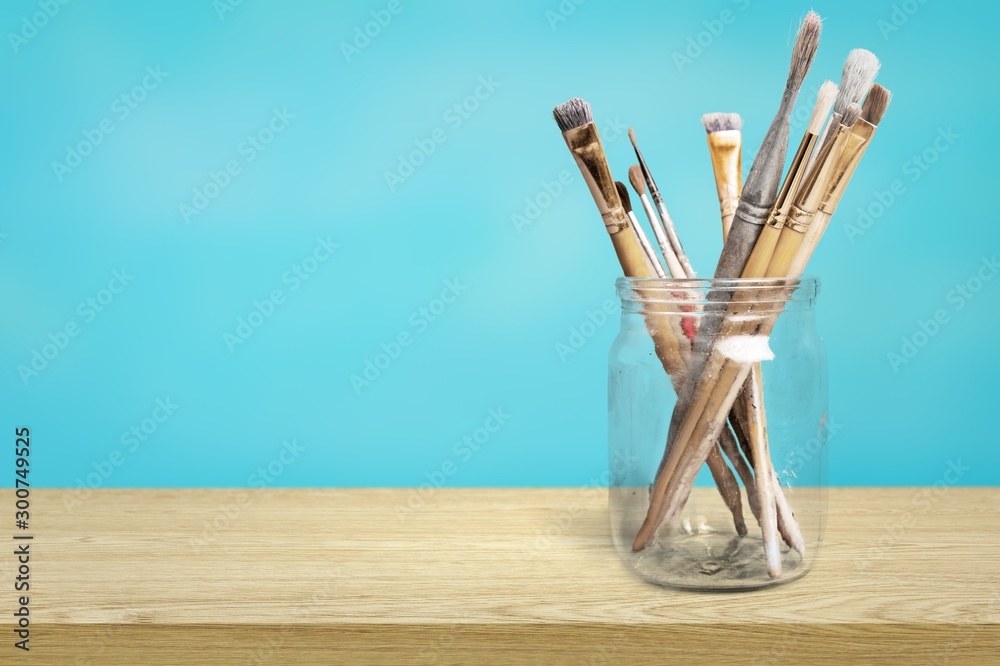 Brushes in a glass jar on the table and white wall