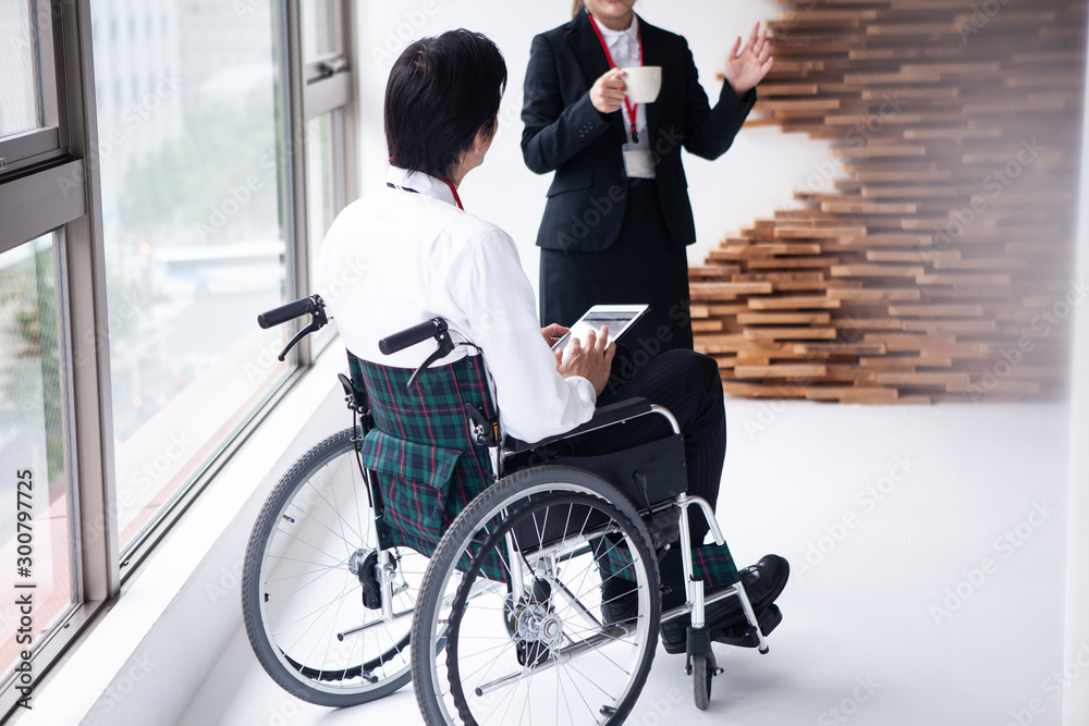 女性社員と談笑する車椅子のビジネスマン