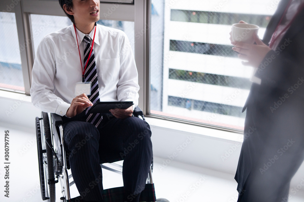 女性社員と会話をする車椅子のビジネスマン