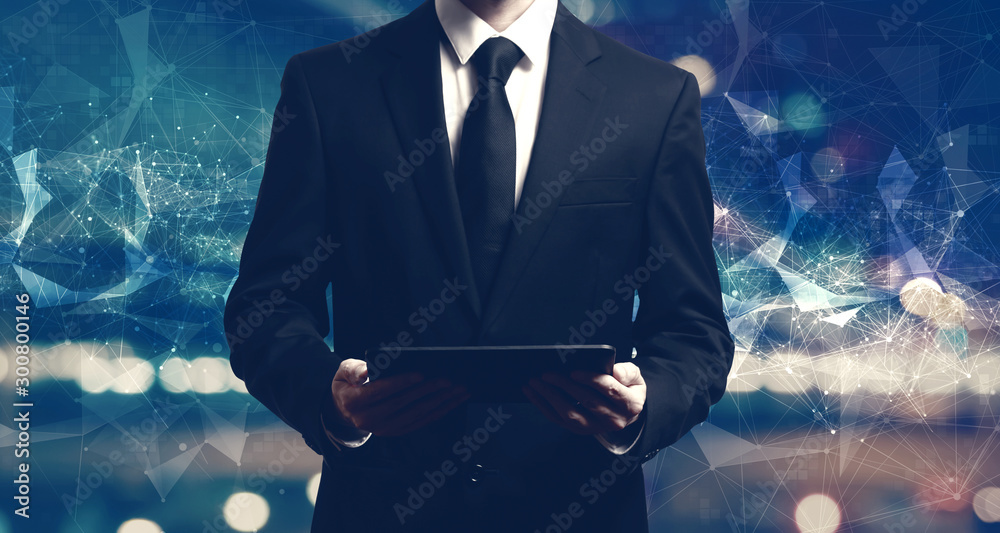 Businessman holding a tablet computer on night city background